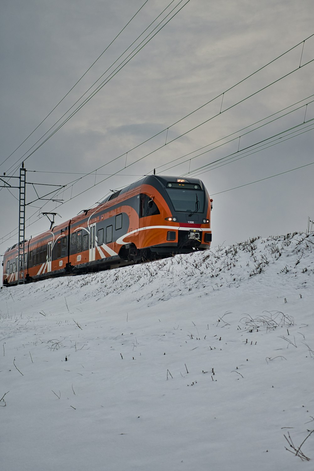orange and black train on snow covered ground during daytime