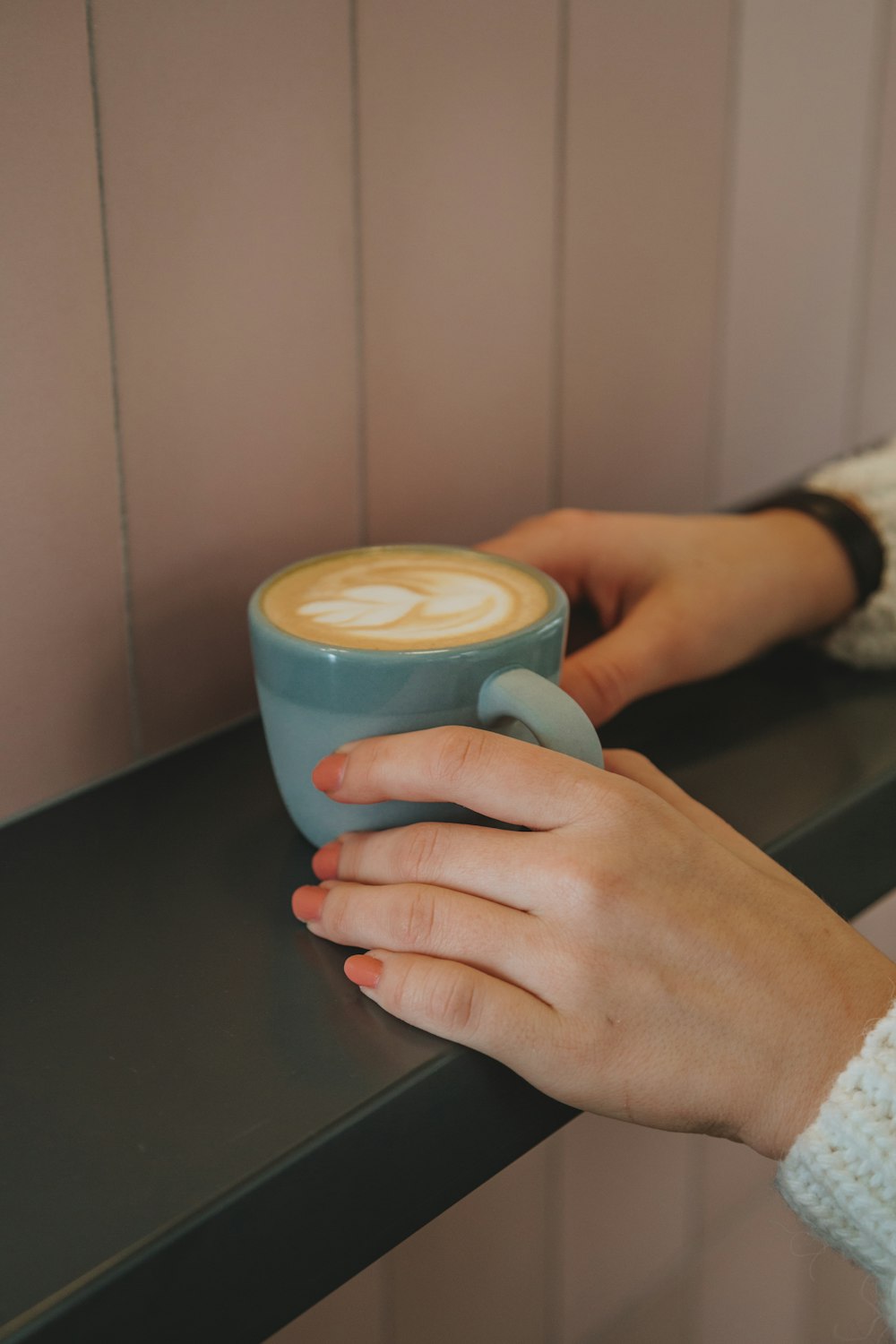 person holding blue ceramic mug with coffee
