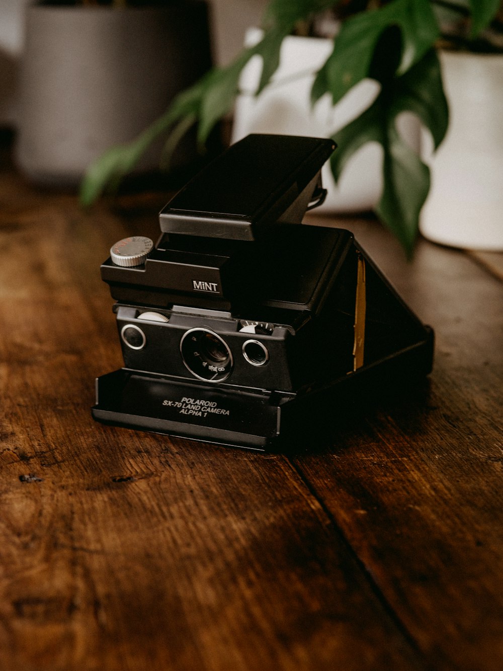 black polaroid camera on brown wooden table