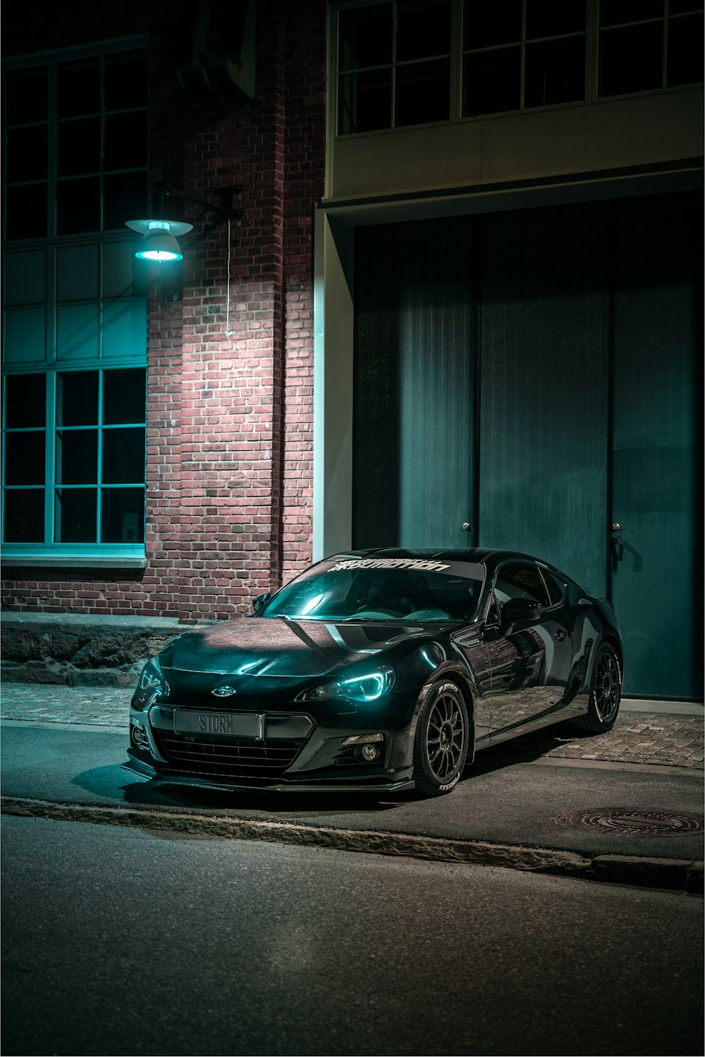 black porsche 911 parked in front of brown brick building