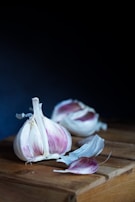 Close-up of garlic cloves being peeled on a wooden cutting board.