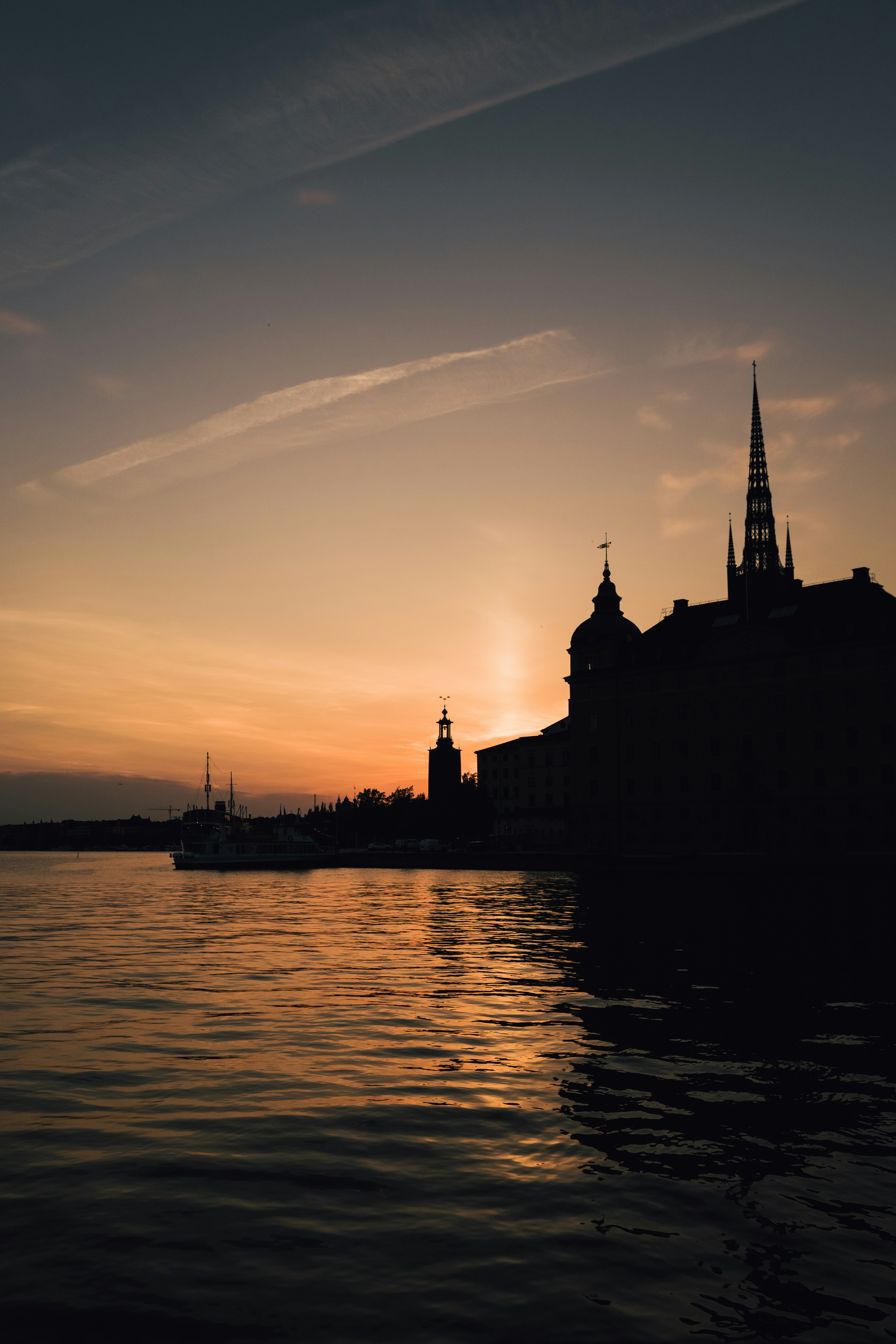 silhouette of building near body of water during sunset