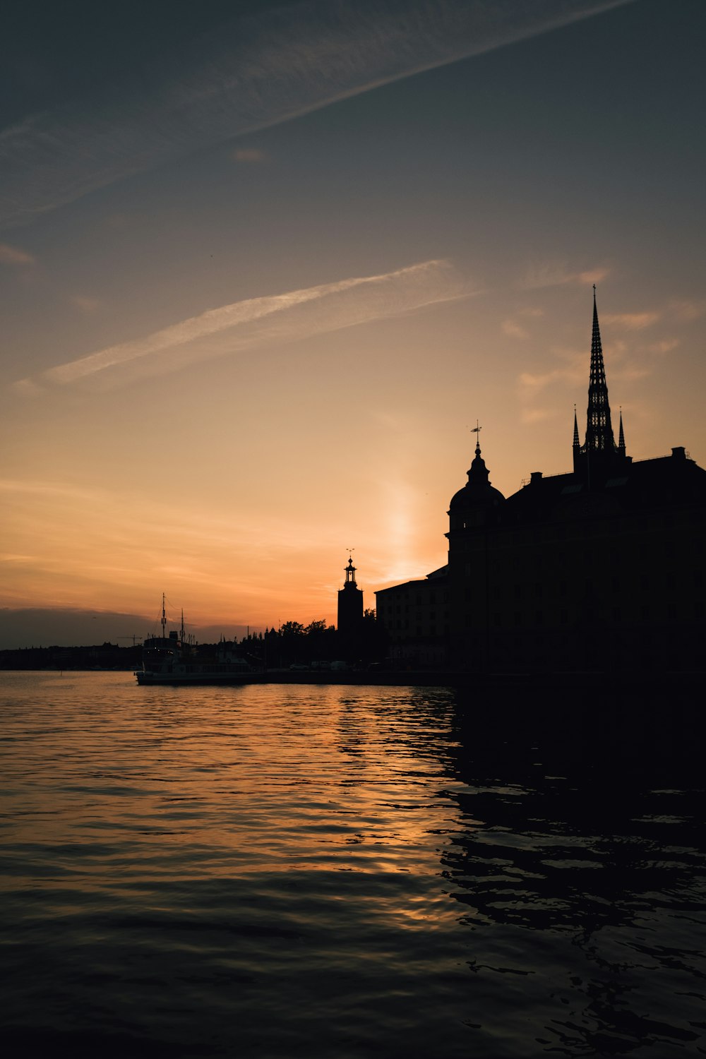 silhouette of building near body of water during sunset