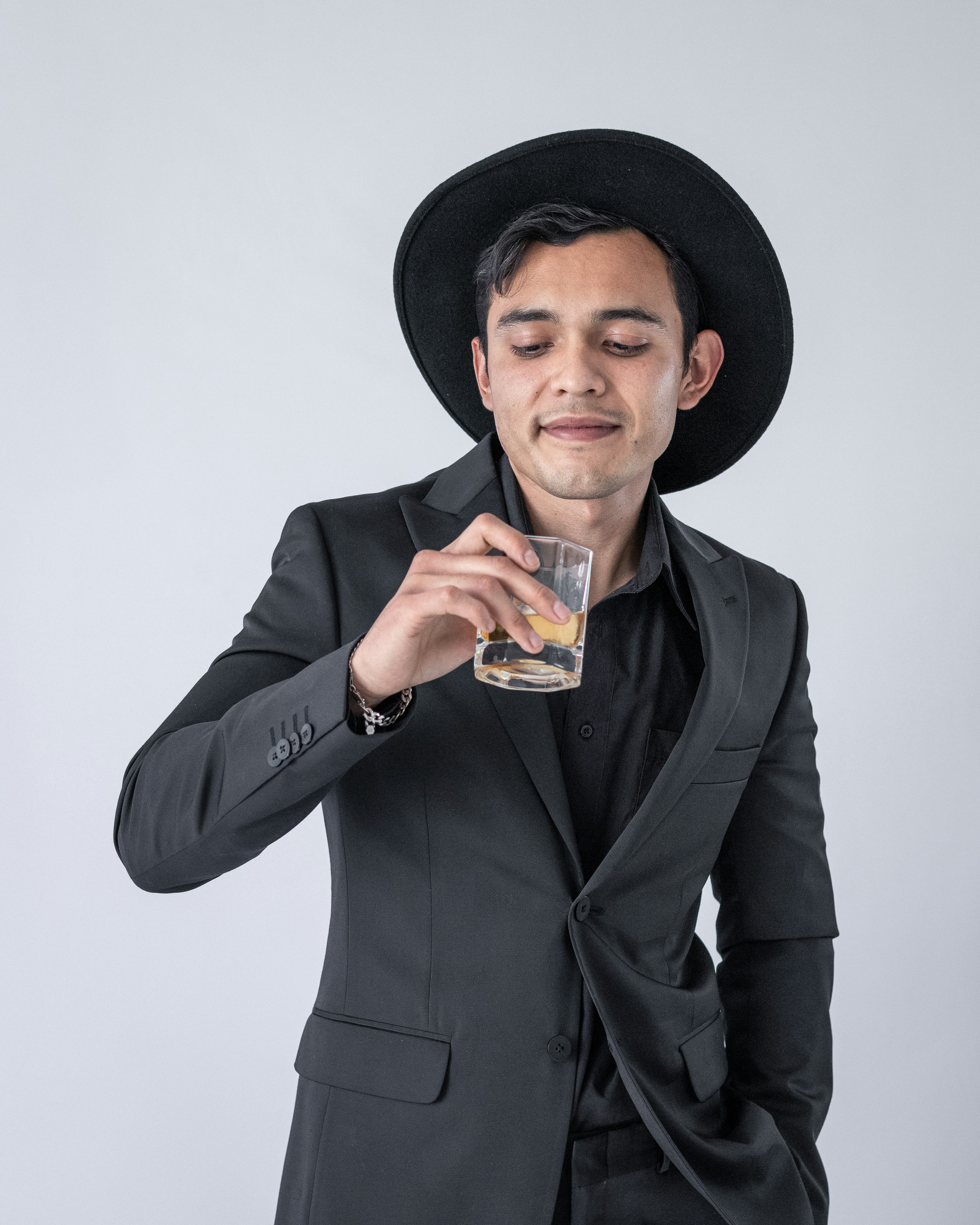 man in black hat holding clear drinking glass
