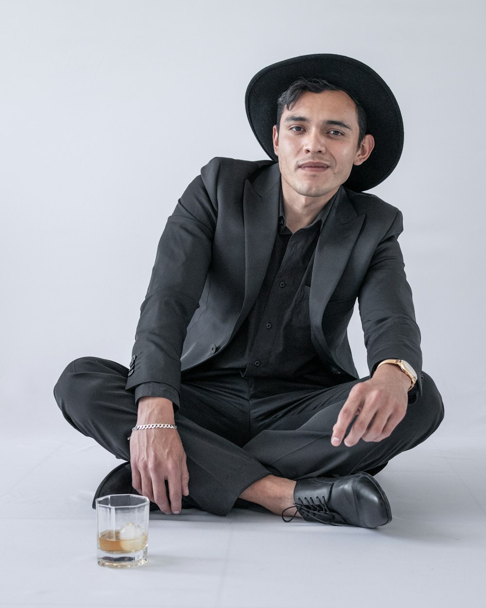 man in black blazer and black pants wearing black hat sitting on floor