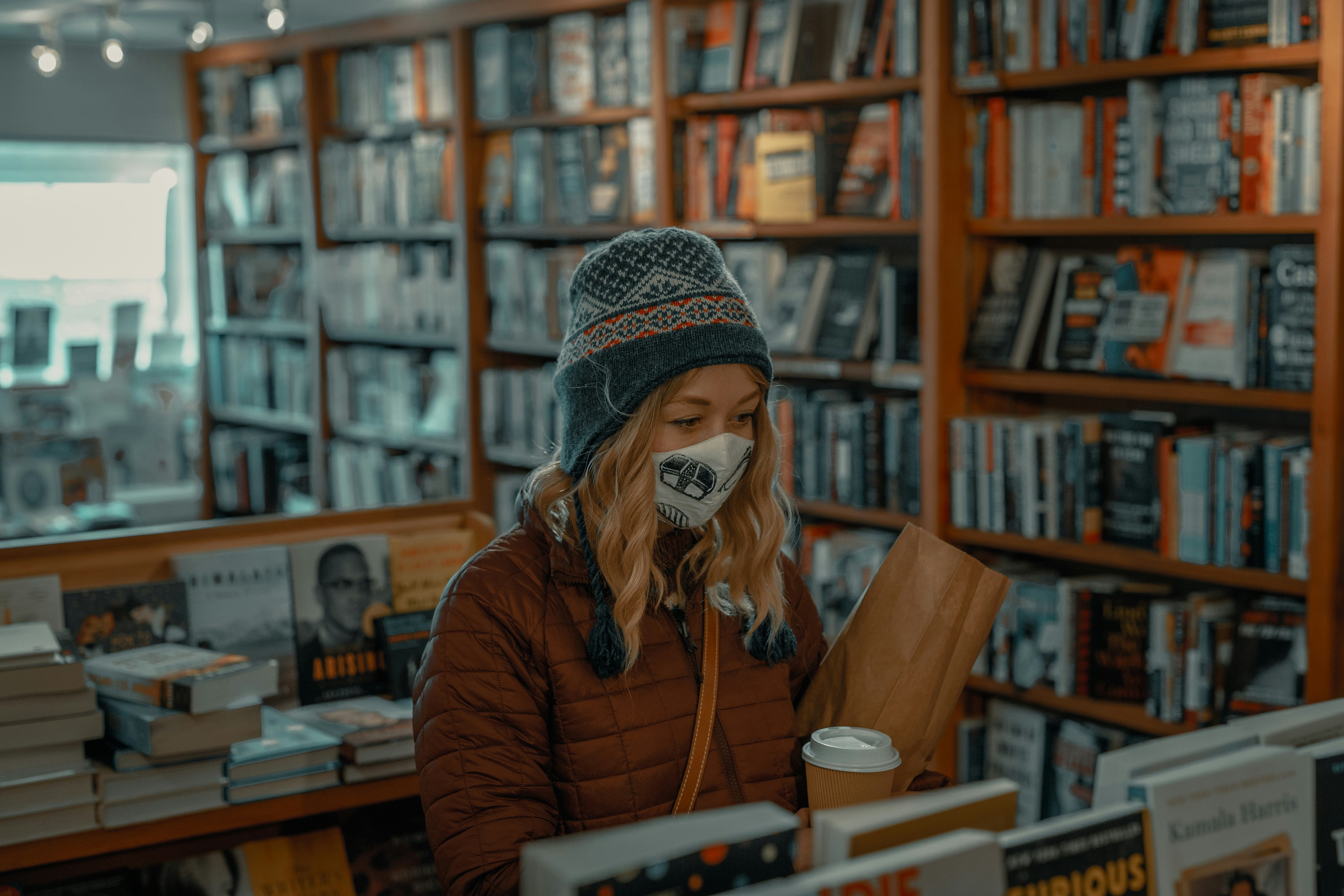 woman in brown jacket holding white ceramic mug