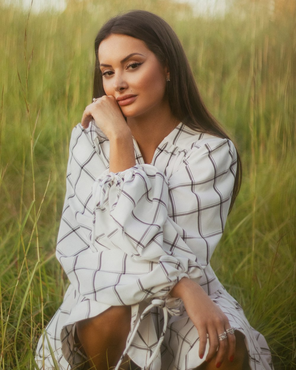 Mujer en vestido floral blanco y negro de pie en el campo de hierba verde durante el día