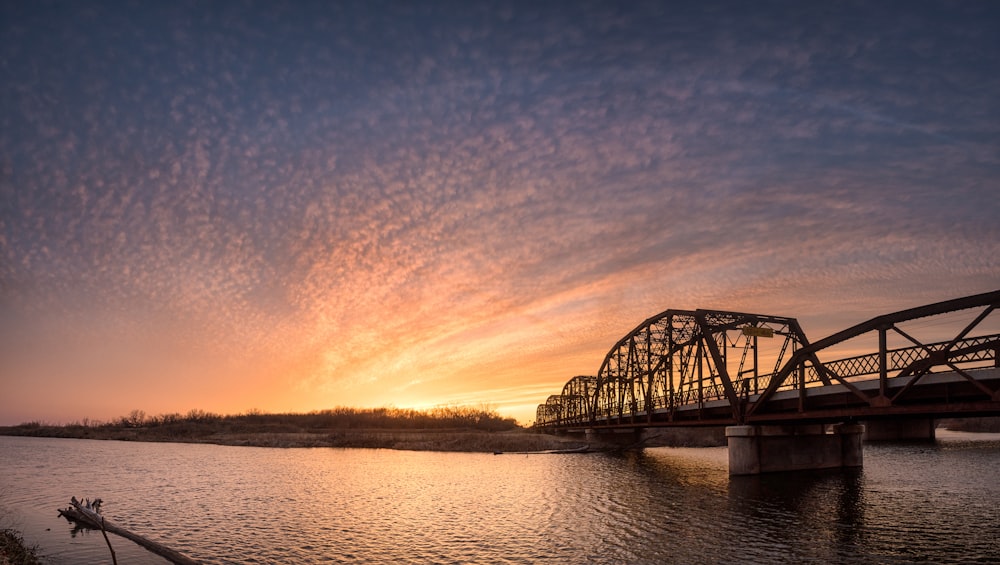 Black Metal Brücke über den Fluss bei Sonnenuntergang