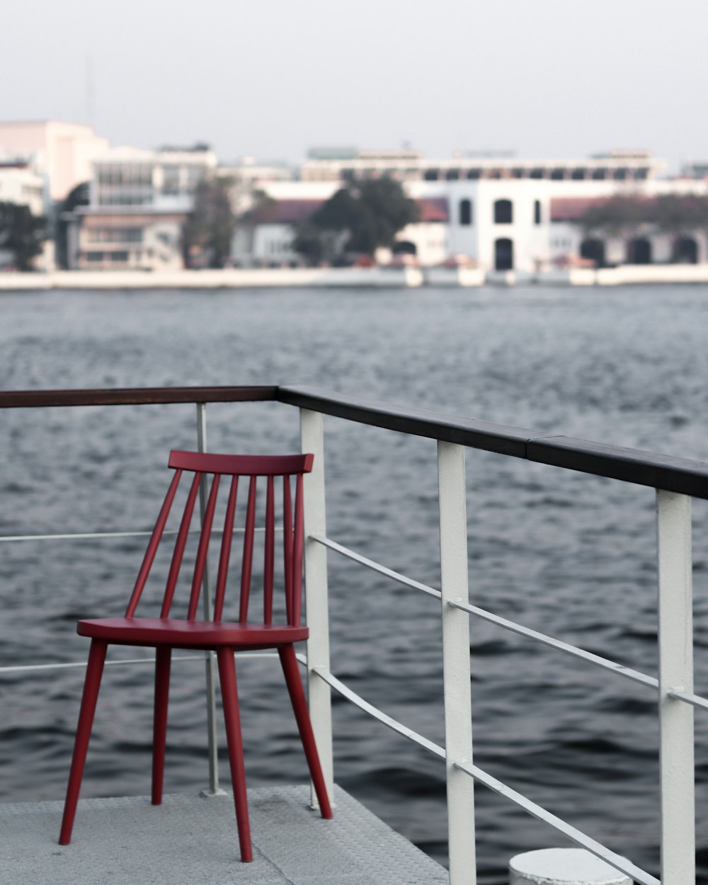 chaise en métal rouge et blanc près d’un plan d’eau pendant la journée