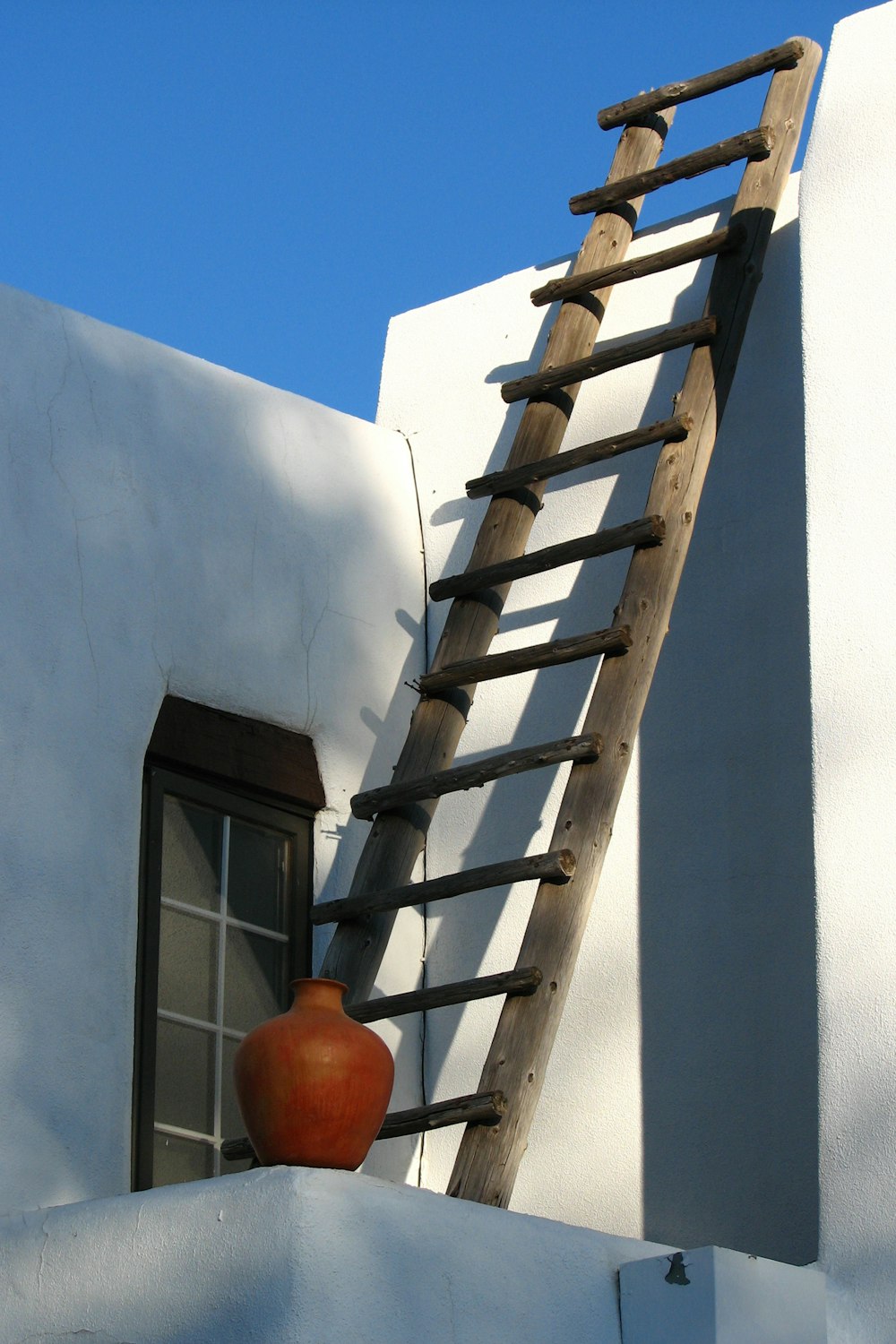 brown wooden ladder on white concrete wall