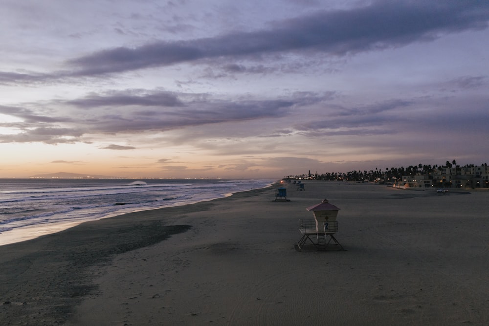 white and black lifeguard chair on beach during sunset