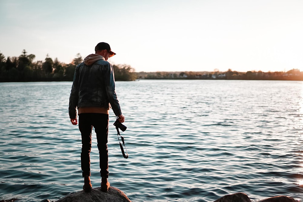 man in blue long sleeve shirt and black pants standing on rock in the middle of near near near near