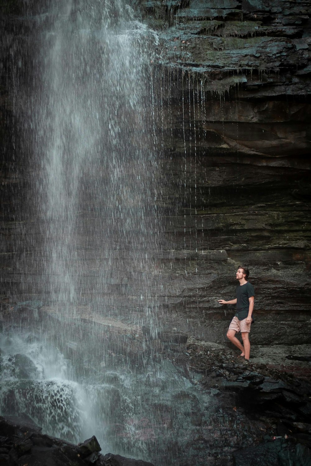 Frau im schwarzen Bikini steht auf Wasserfällen