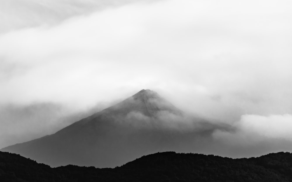 grayscale photo of mountain under cloudy sky