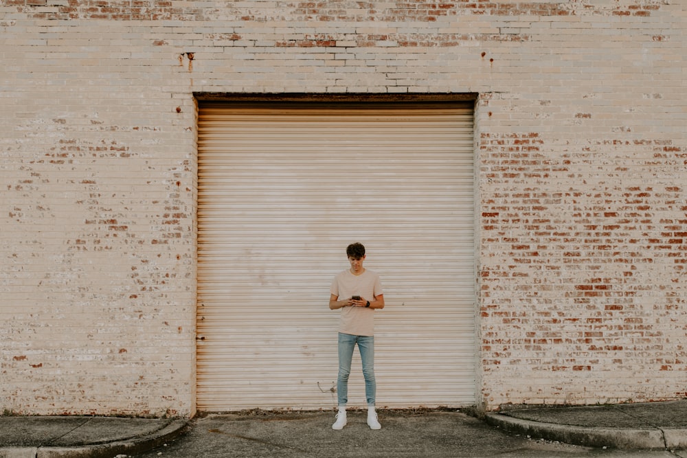 woman in white shirt and blue denim jeans standing beside white wall during daytime