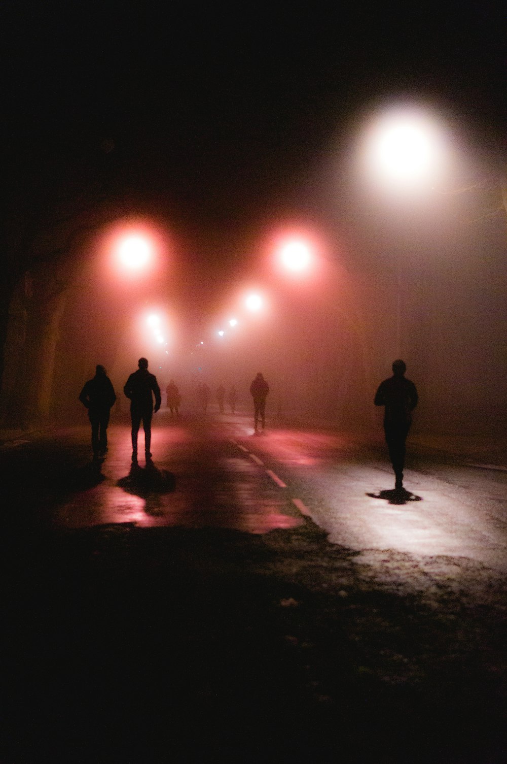Silhouette von Menschen, die nachts auf der Straße gehen