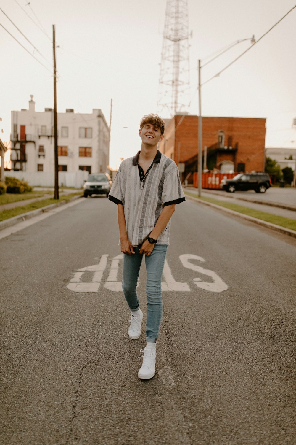 woman in white and black long sleeve shirt and blue denim jeans standing on road during