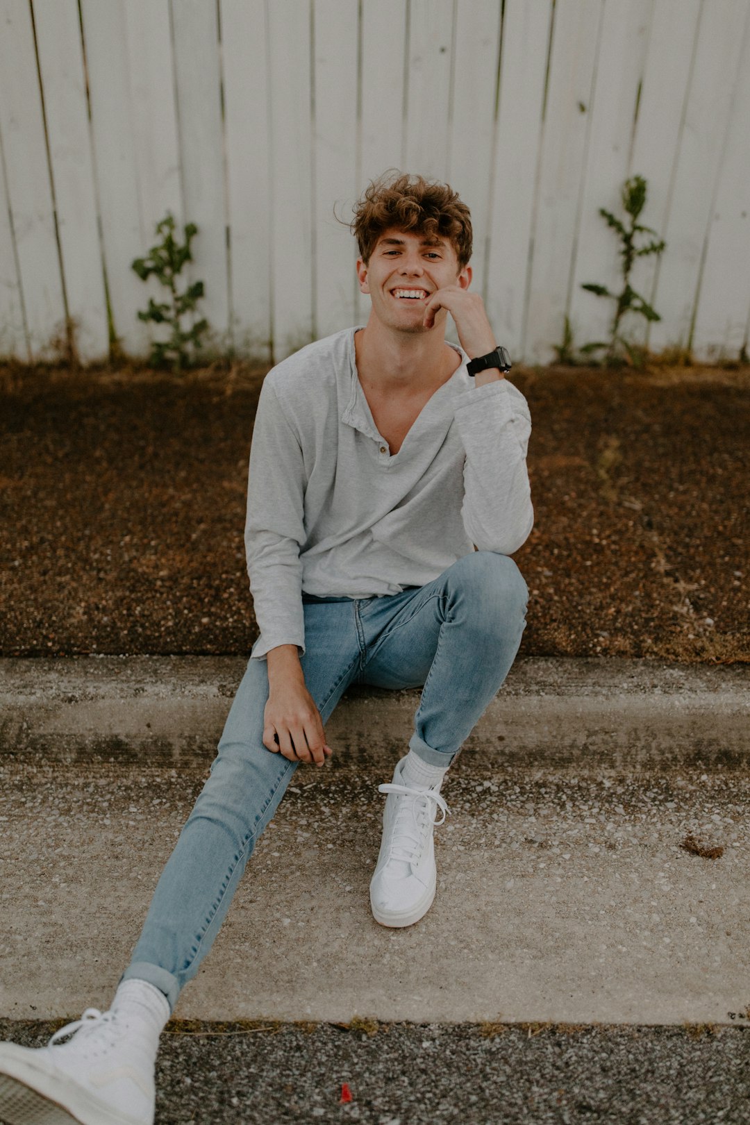 woman in beige sweater and blue denim jeans sitting on gray concrete floor