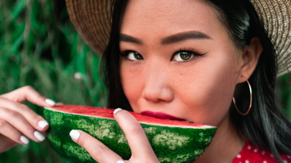 woman in brown sun hat holding sliced watermelon