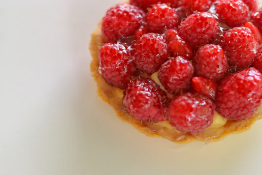Close-up of an elegant gourmet pastry with delicate icing and fresh berries on a rustic wooden table.