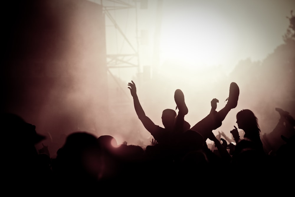 silhouette of people raising their hands