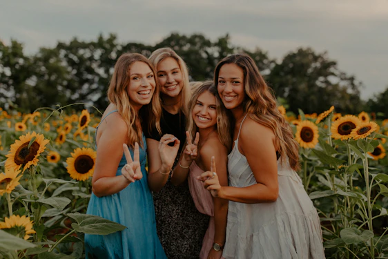 A diverse group of women and girls smiling and holding hands in a sunlit community garden.