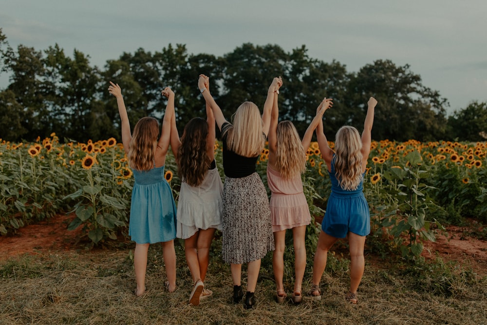 groupe de filles debout sur le champ de tournesol pendant la journée