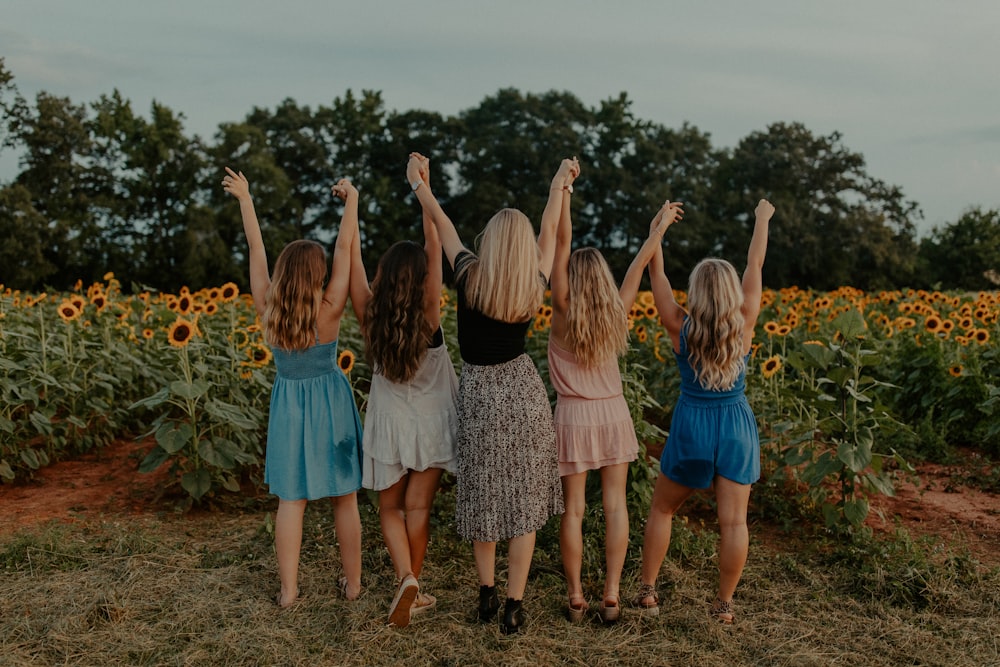 Gruppe von Mädchen, die tagsüber auf dem Sonnenblumenfeld stehen