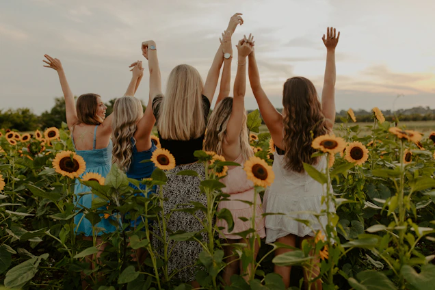 A group of diverse volunteers joyfully planting sunflowers in a community garden under warm sunlight.
