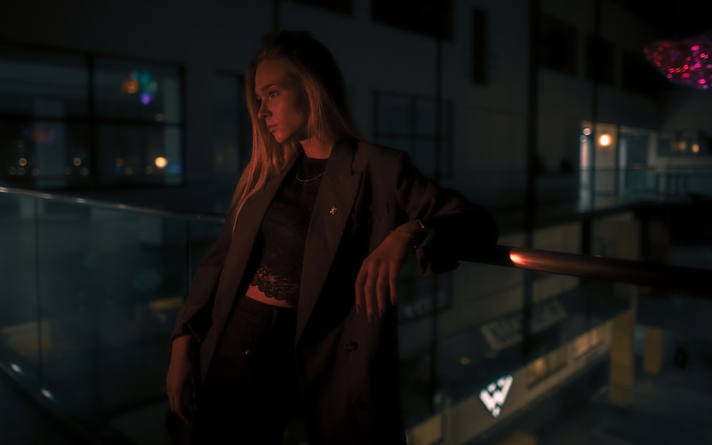 woman in black coat standing near glass window