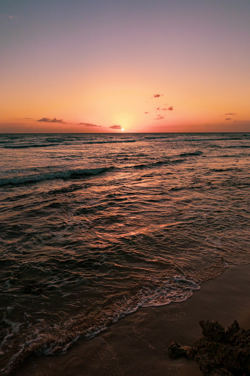 ocean waves crashing on shore during sunset