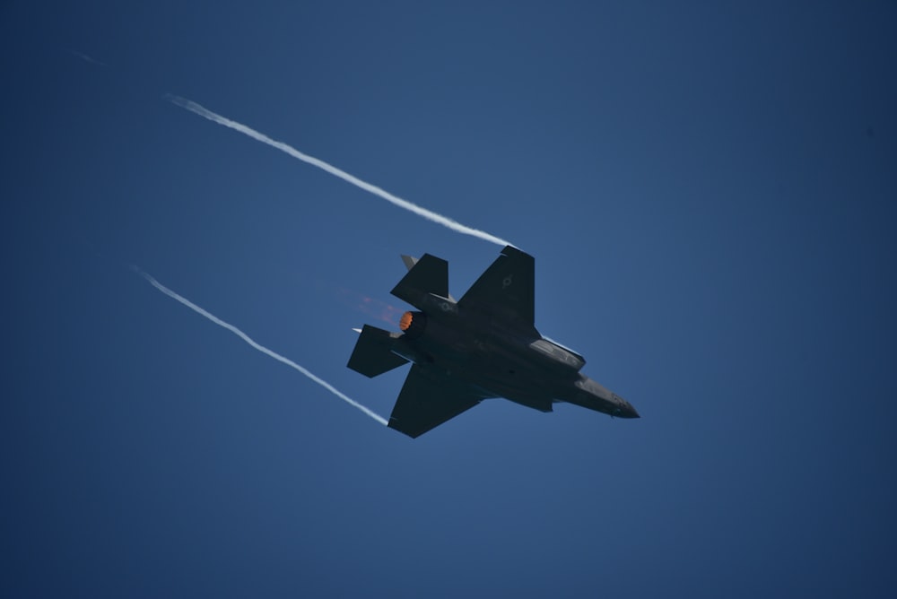 black jet plane in mid air under blue sky during daytime