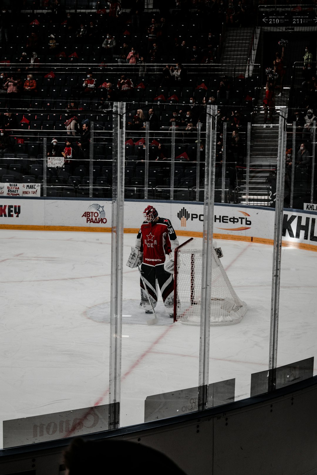 man in red jersey shirt and black pants standing on ice hockey field