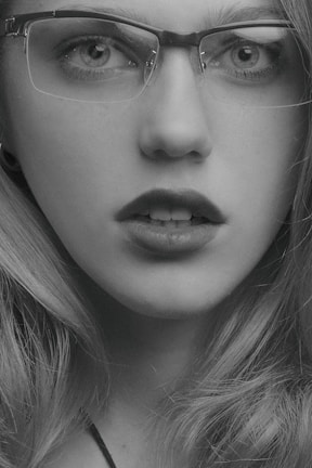 Close-up of a woman smiling while wearing sleek black-rimmed glasses.