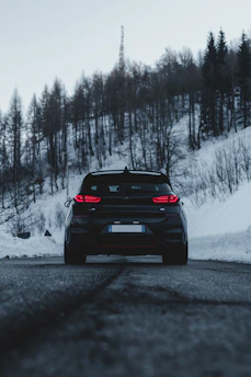 A sleek black SUV parked against a snowy alpine mountain backdrop at sunrise.