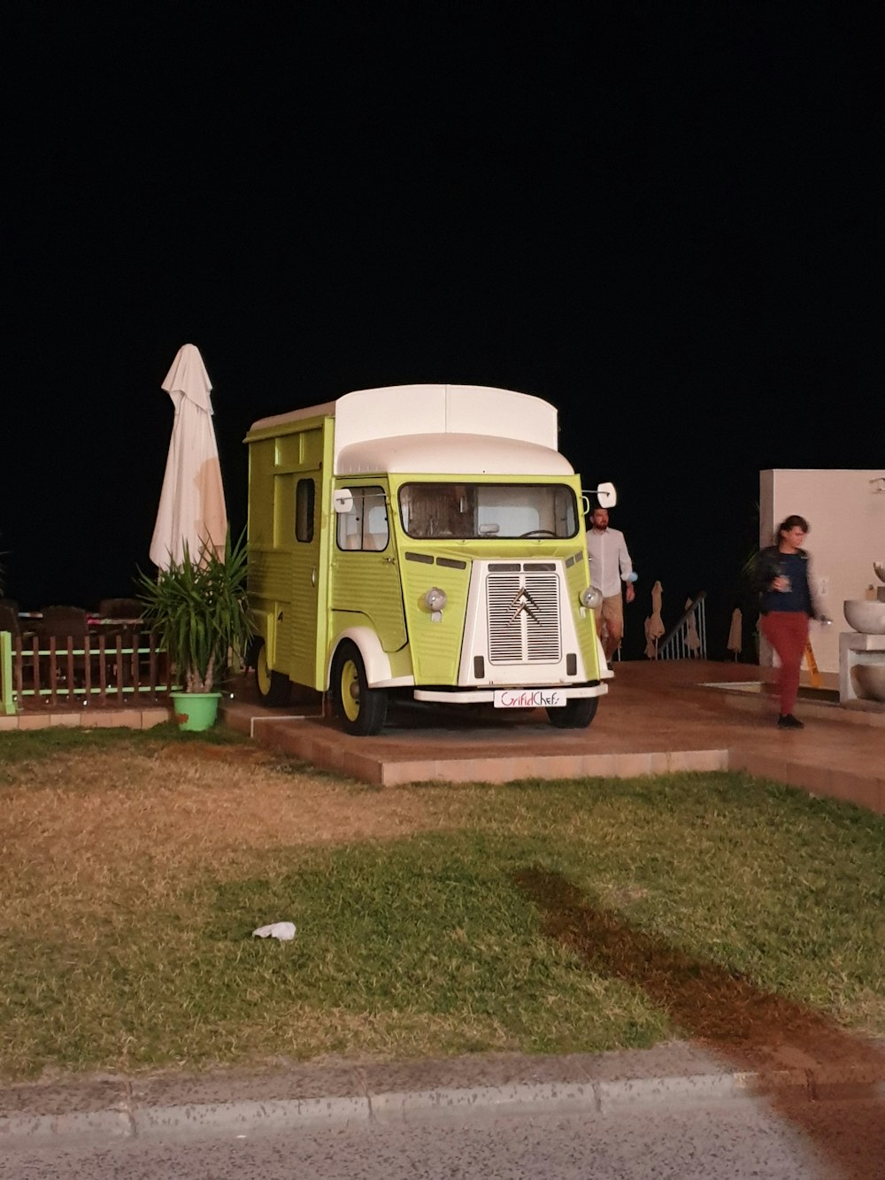 man in white t-shirt standing beside green and white van during nighttime