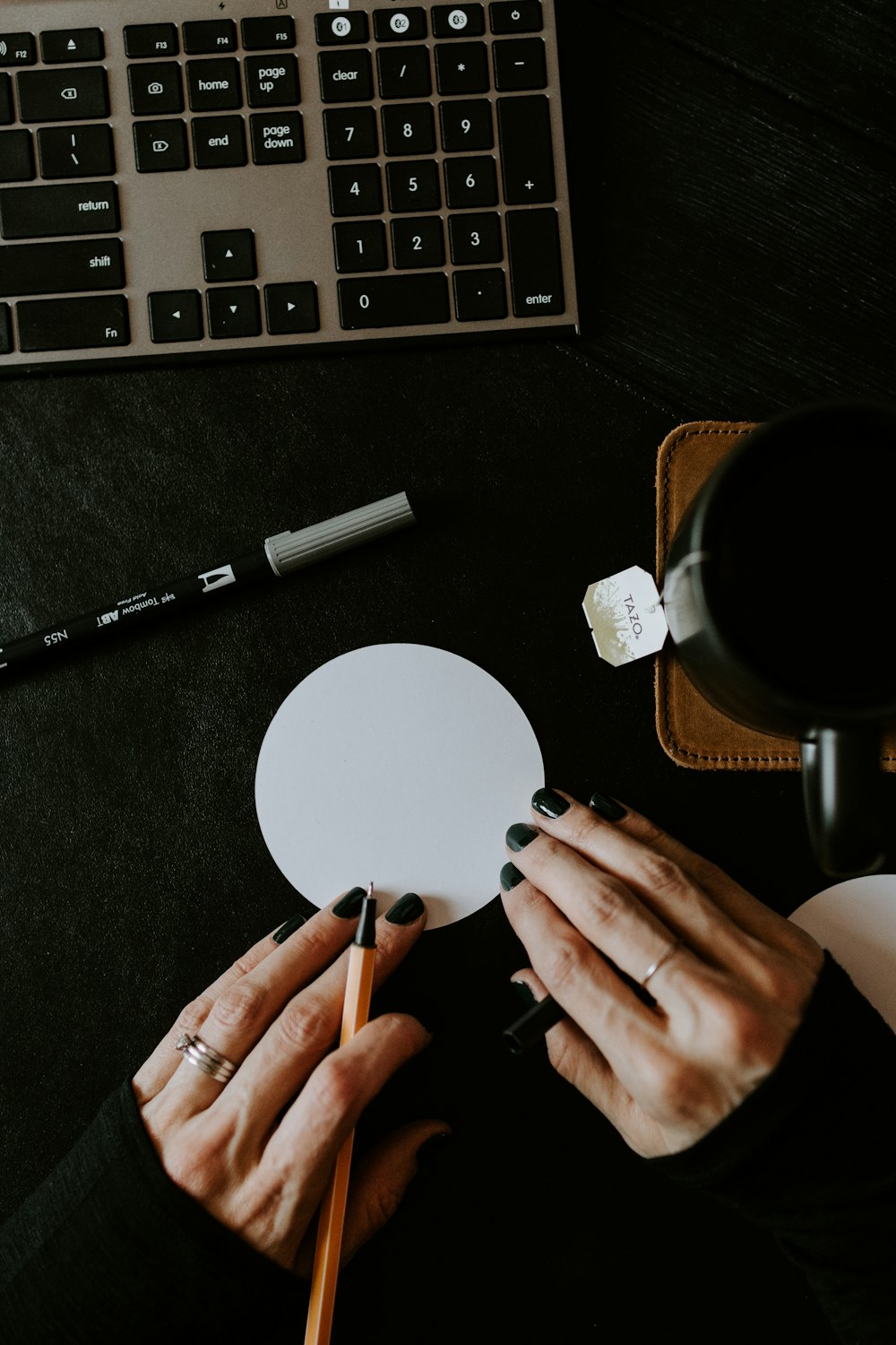 person holding black pen and white round paper