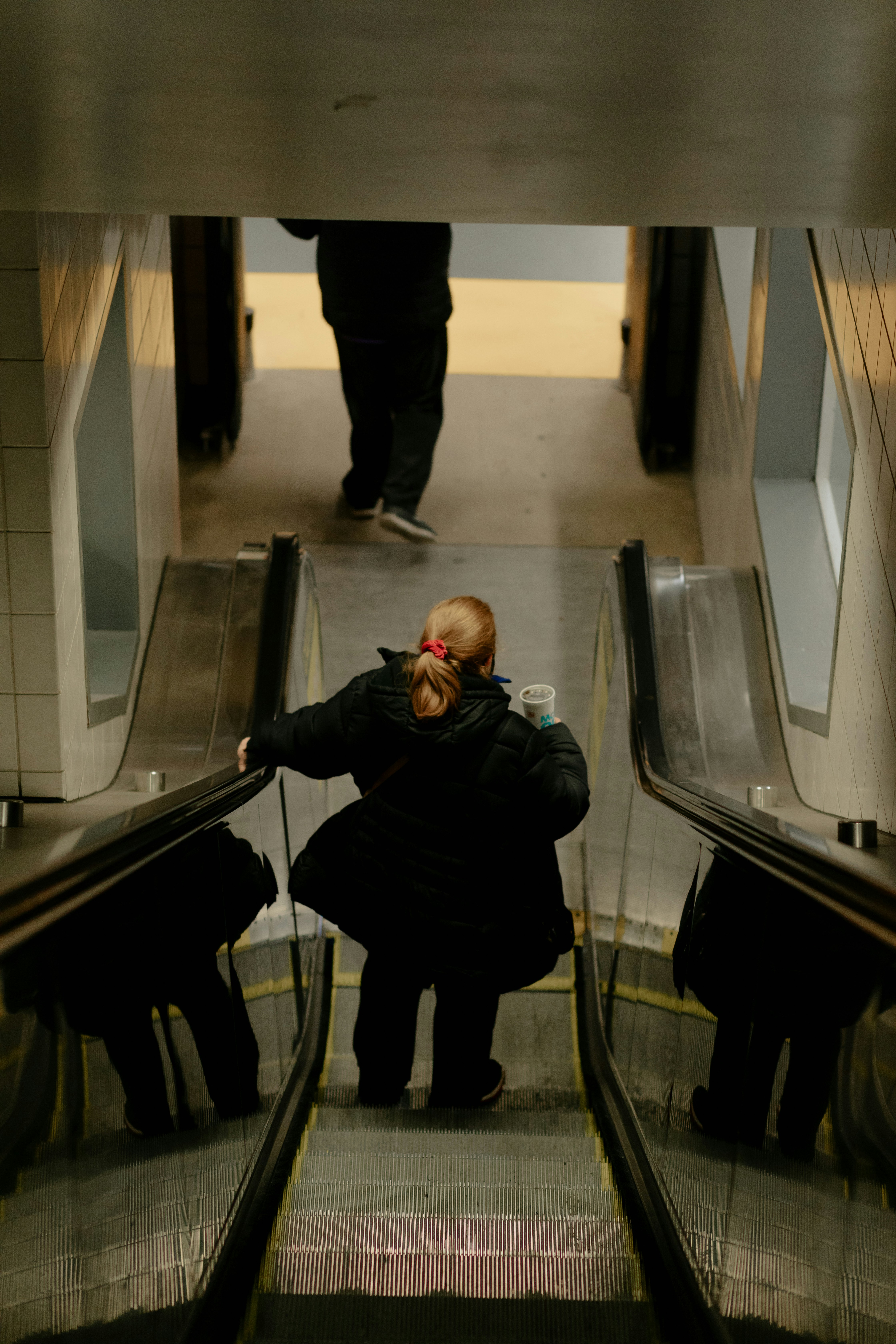 man in black jacket and black pants standing on escalator