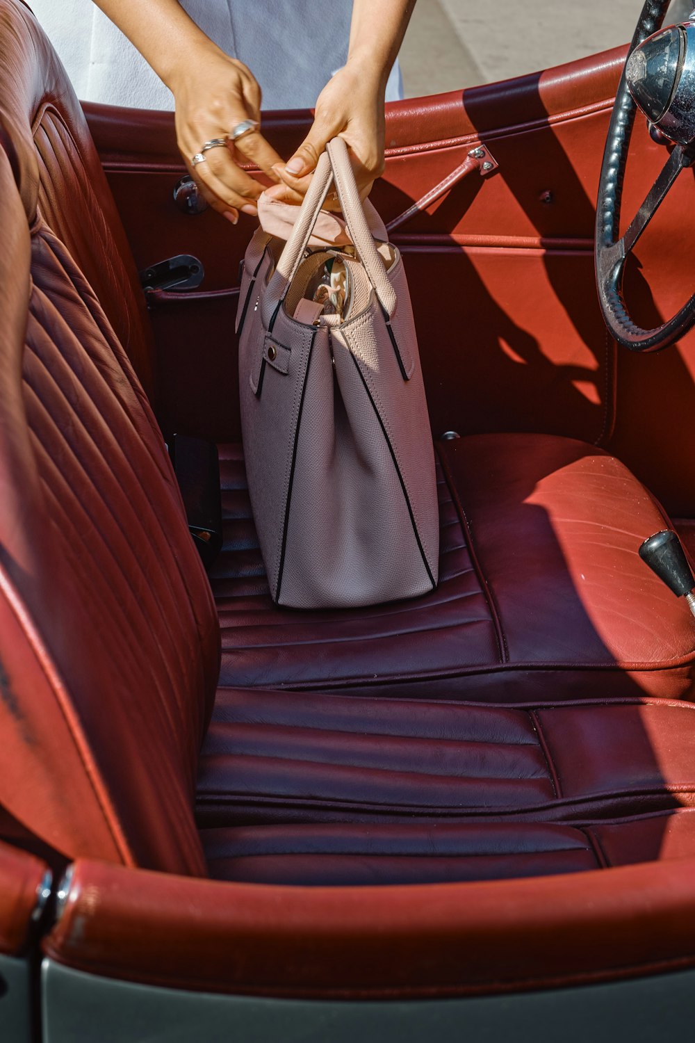 gray leather handbag on brown leather car seat