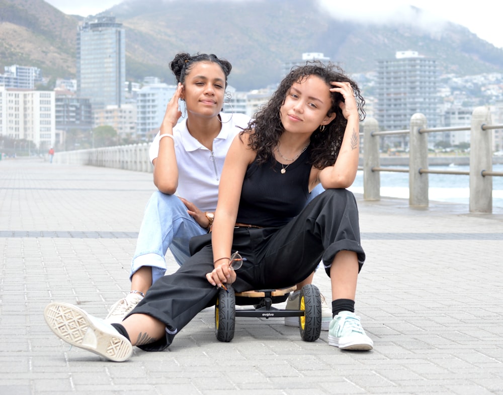 woman in black sleeveless dress sitting on wheel chair beside woman in blue sleeveless dress