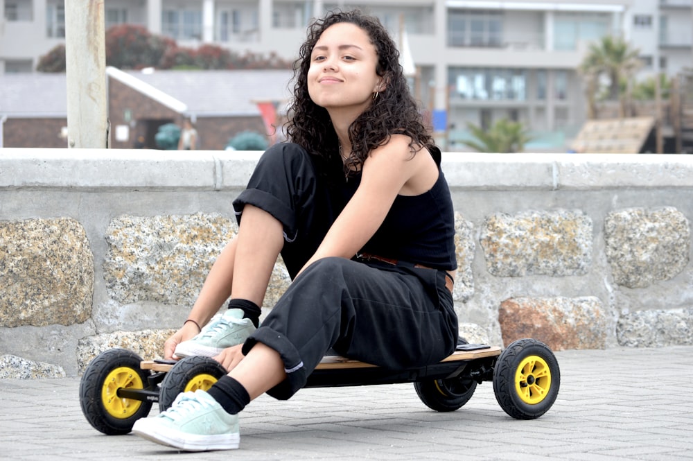 Frau in schwarzem T-Shirt und blauen Jeansshorts sitzt auf schwarzem Rollstuhl