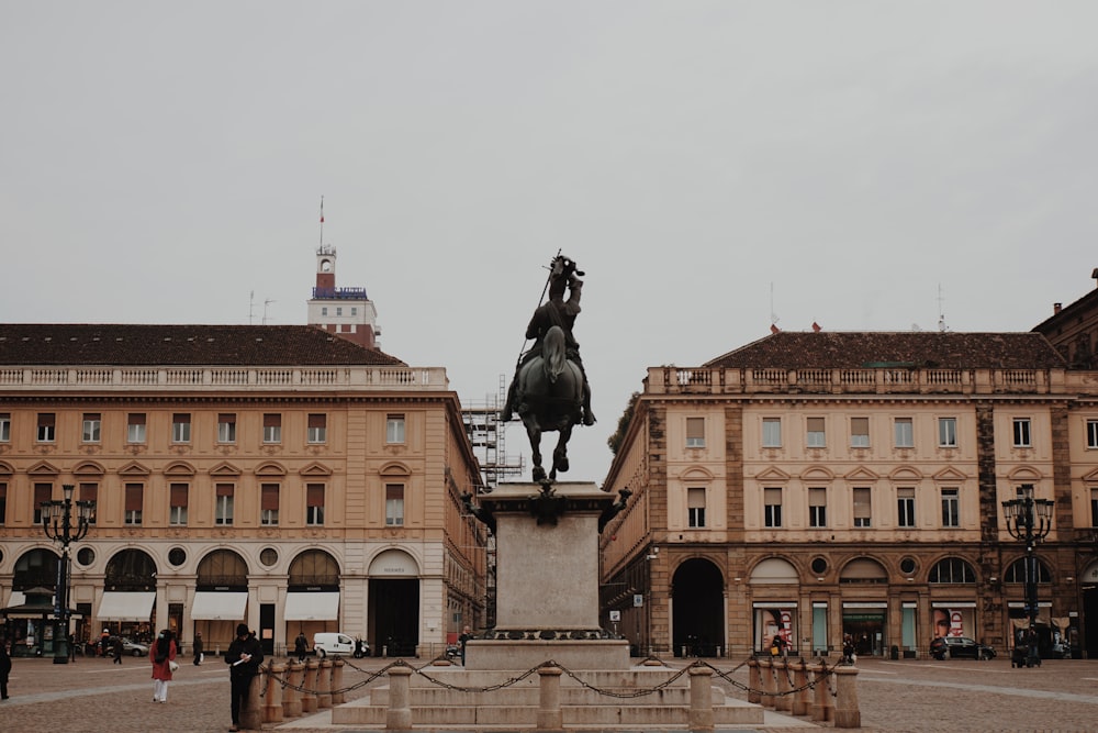 estátua preta do cavalo perto do edifício de concreto marrom durante o dia