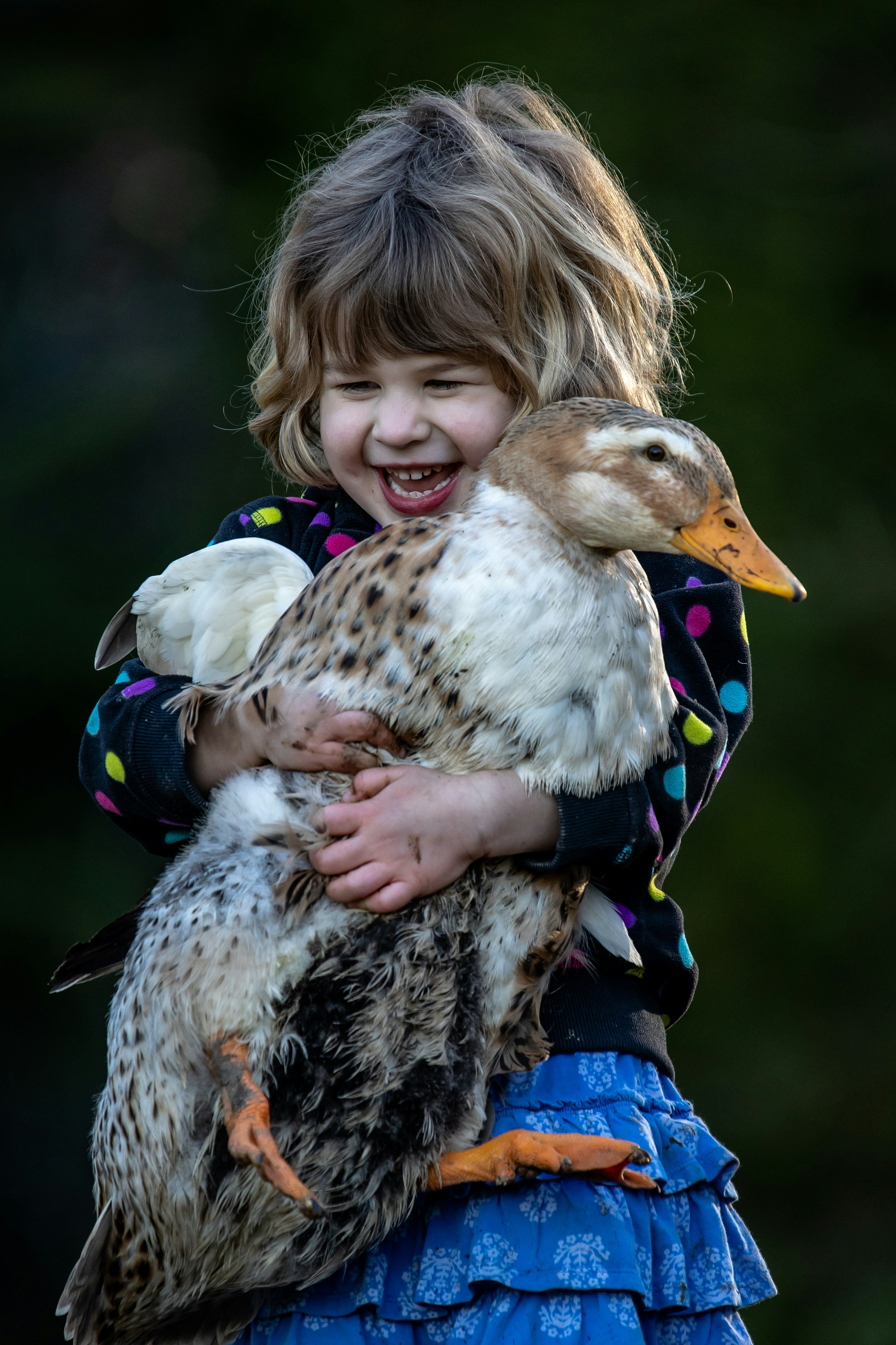 girl in blue and black jacket holding white and black duck