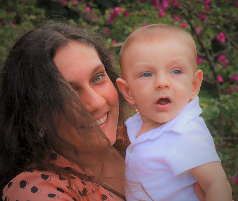 woman in orange and black shirt carrying baby in white shirt