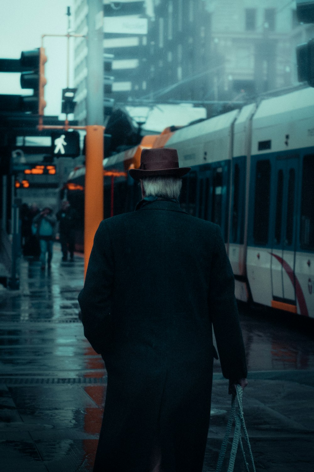 man in black jacket and brown hat standing in front of white train