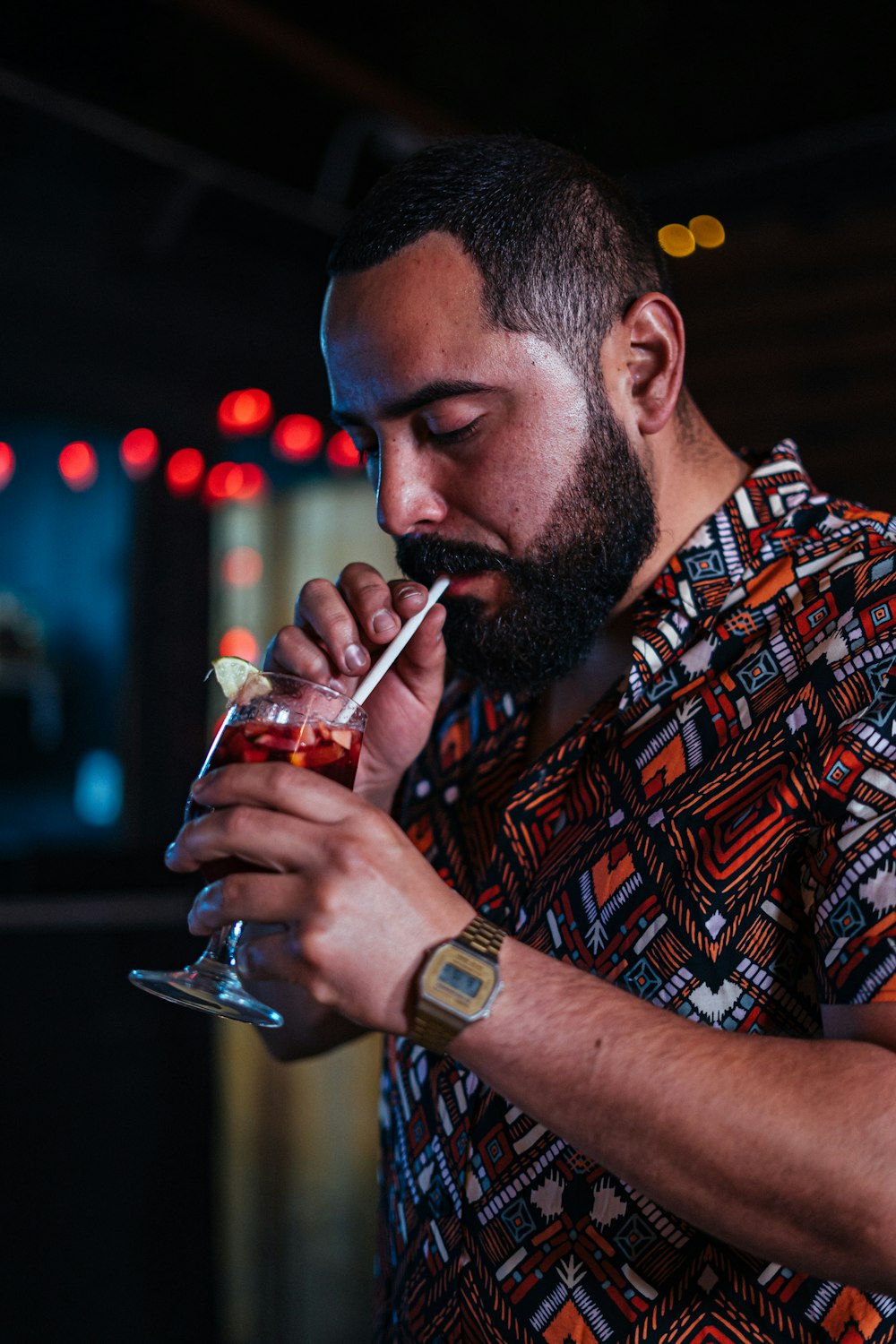 homme en chemise boutonnée à carreaux rouge et noir buvant dans un verre à boire transparent