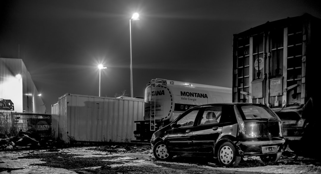 grayscale photo of a truck in front of a building