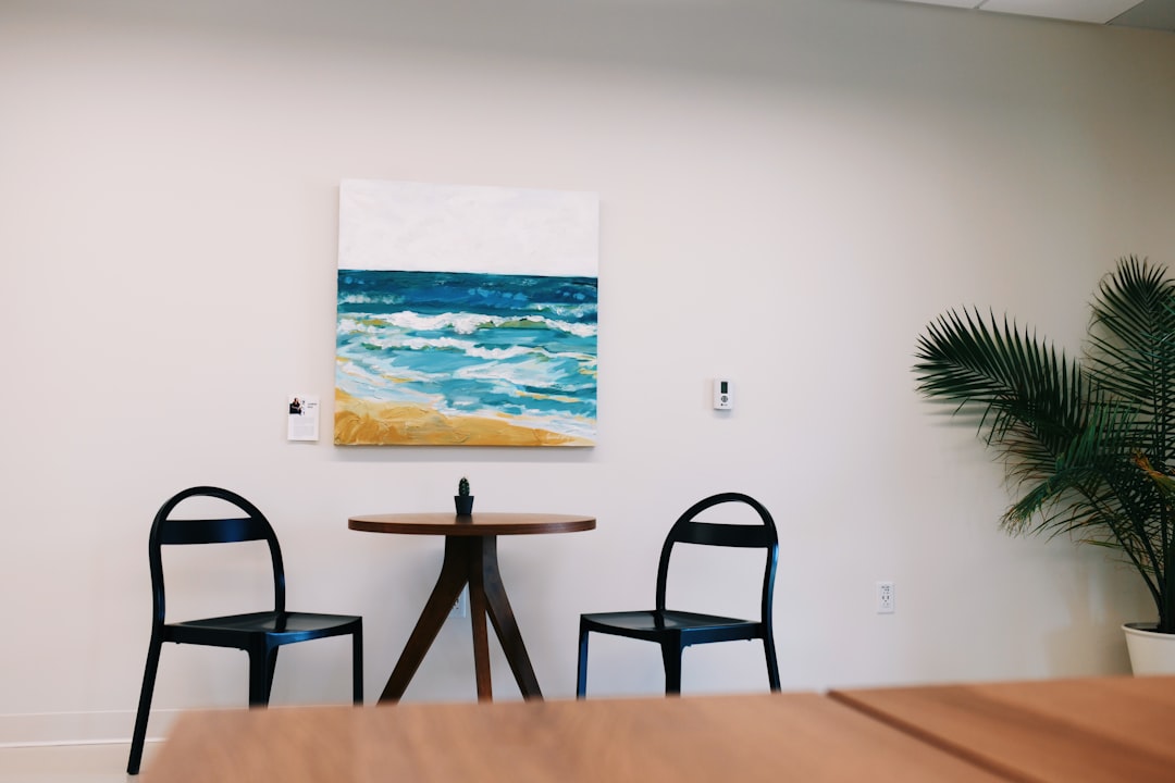 black wooden table and chairs near sea painting
