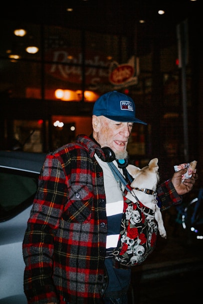 man in red black and white plaid coat holding brown short coated dog