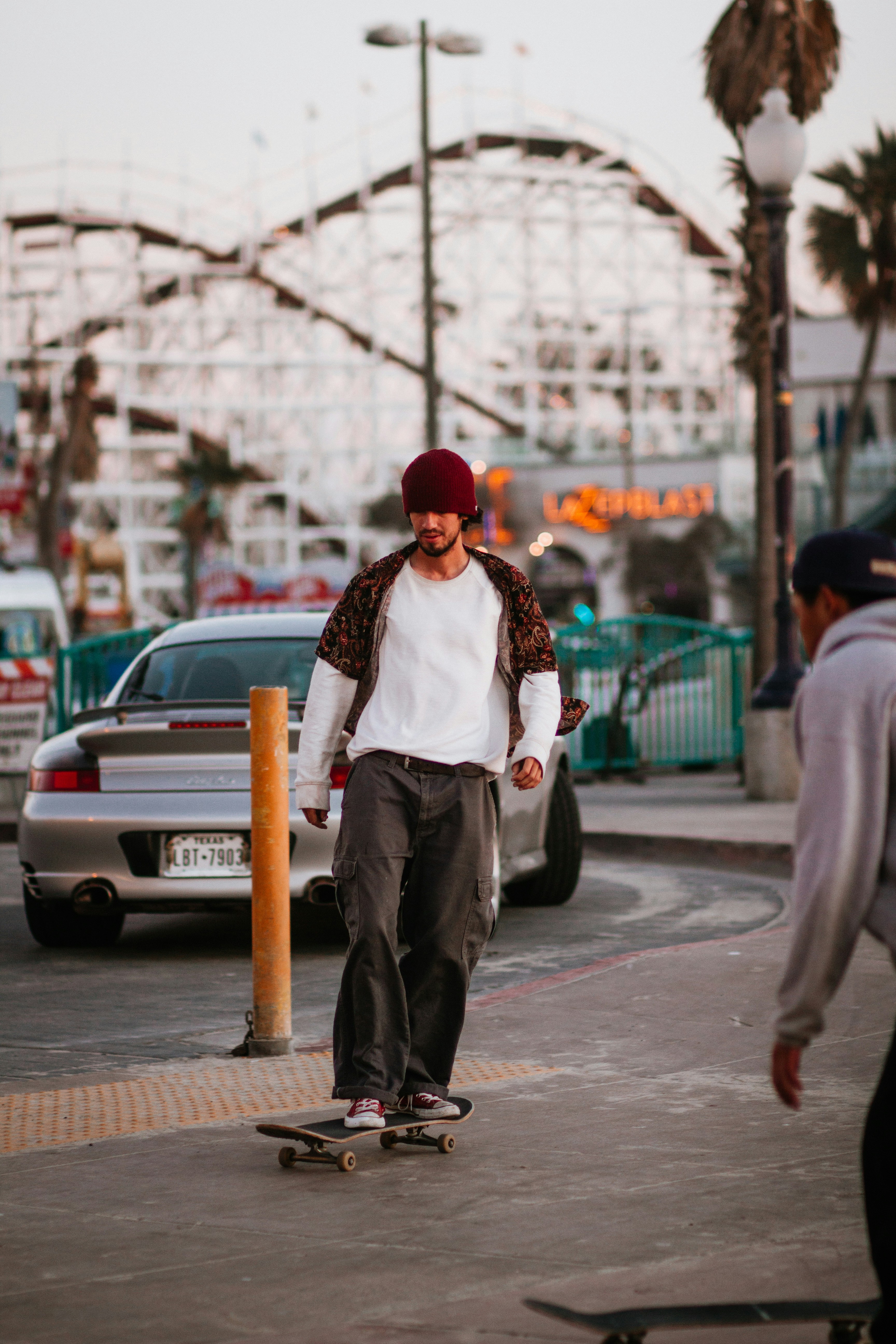 man in red knit cap and gray coat standing on sidewalk during daytime